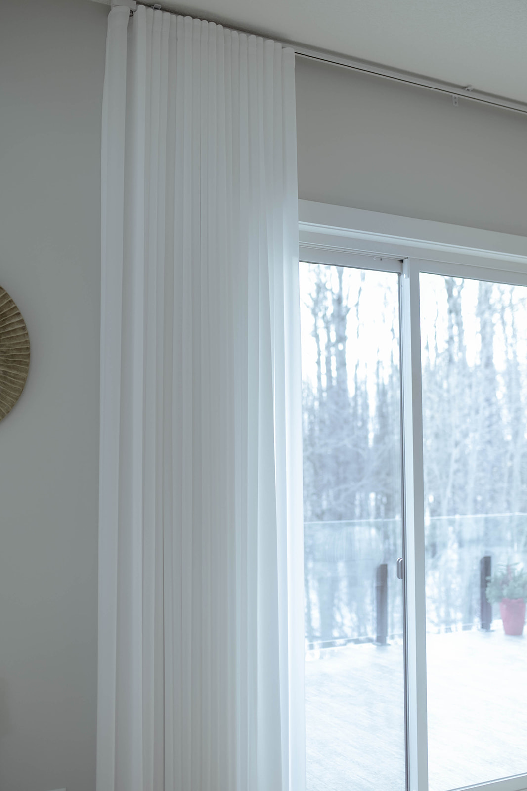 Sheer fabric gathered beside a sliding door, with the handle and overhead track visible